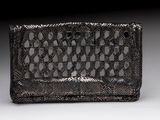 une image représentant un sac à main noir et argenté posé sur une surface blanche