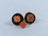 a pair of black and red stud earrings with gold accents