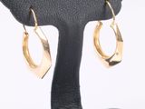 pair of gold toned hoop earrings on a black stand