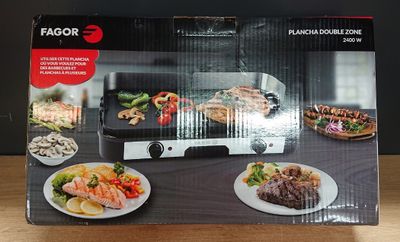 emballage représentant une boîte noire et blanche avec l'image d'un barbecue et d'assiettes de plats posées sur une table