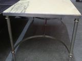 une table en marbre avec des pieds en métal et un plateau en marbre