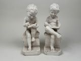 two figurines of children sitting on blocks
