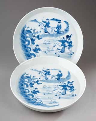 pair of blue and white plates with dragon designs on them