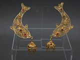 a close up of a pair of gold earrings on a clear stand
