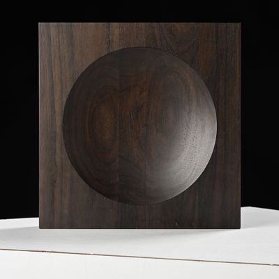 un objet en bois posé sur une surface blanche, sur fond noir