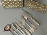 un service d'argenterie sur une table à côté d'une boîte