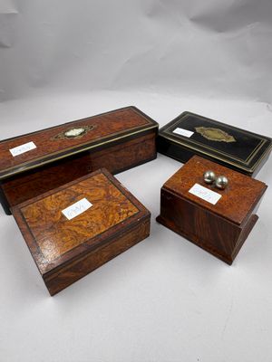 trois boîtes en bois portant des étiquettes, posées sur une surface blanche