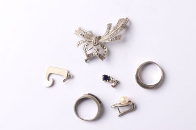 five different rings and a brooch on a white surface