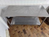 a stainless steel table in the middle of a tiled floor