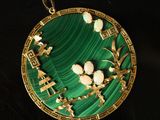gold and green broochle with flowers on it on a black surface