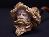 une vieille pipe surmontée d'un visage d'homme coiffé d'un chapeau