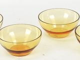 four yellow glass cups sitting on top of a white surface