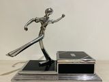 statue of a man holding a tennis racquet on top of a wooden table