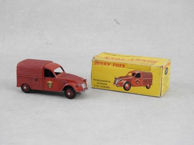 un petit camion rouge en plastique à côté d'une boîte jaune