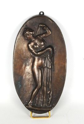 une image représentant une plaque en bronze sur laquelle figure une femme tenant un oiseau