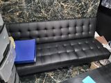 a black leather couch with a blue folder on it