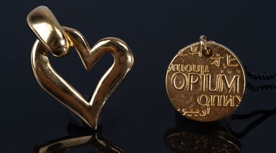 deux pendentifs en forme de cœur dorés posés sur une surface noire, sur fond noir