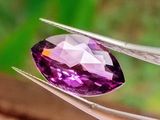 une personne tenant une pince ornée d'une pierre précieuse violette