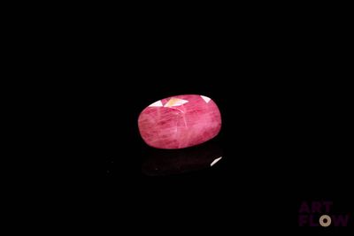 a close up of a pink stone on a black surface