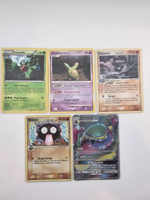 Plusieurs cartes Pokémon sont posées sur une surface blanche, sur fond blanc.