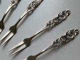 four forks and spoons are sitting on a table with a spoon in the middle of them