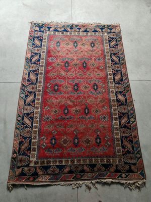 a red rug with a blue border on a white floor