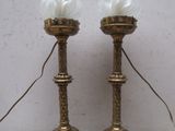 une paire de bougies anciennes en laiton ornées de plumes blanches, posées sur une table