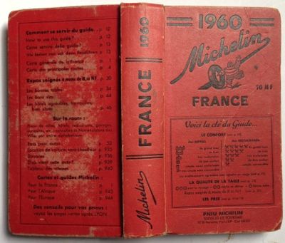 an old book with a red cover sitting on top of a table