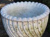a large white urn sitting in the middle of a garden