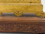 a gold clock sitting on top of a wooden stand