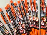 several orange and black pens are lined up on a white surface
