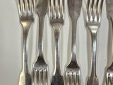 five forks and a knife on a white table