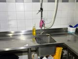a kitchen with a sink, counter, and trash can in it