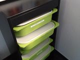 une étagère noire sur laquelle sont posés des récipients verts