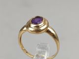 an image of a gold ring with a purple stone in the center