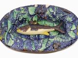 une assiette sur laquelle est posé un poisson, posée sur un fond blanc