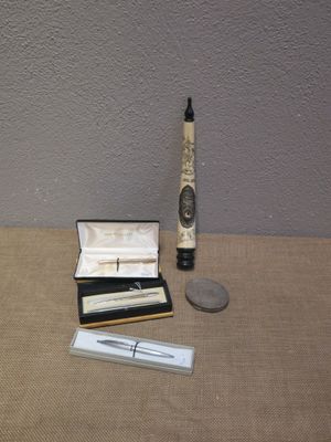 a silver pen and a silver pen sitting on a table next to a silver coin
