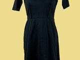 une robe noire posée sur un mannequin, sur fond jaune