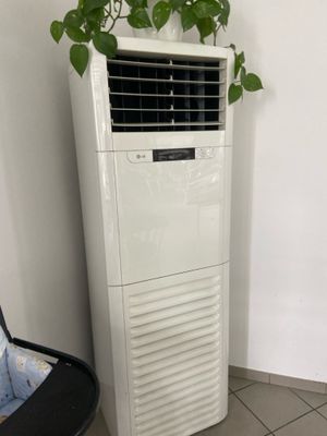 un climatiseur posé sur un sol carrelé, à côté d'une chaise