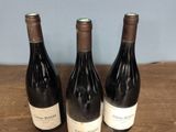 three bottles of wine sitting on top of a wooden table