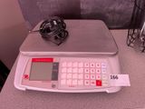 une balance électronique posée sur une table, reliée par un câble