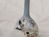 a small vase with a bird on it on a white surface