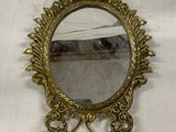 un miroir plaqué laiton posé sur une table blanche recouverte d'une nappe blanche