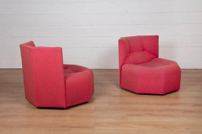 une paire de chaises pivotantes rouges dans une pièce blanche avec un parquet