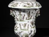 a white vase with green and brown designs on it