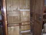 un placard avec une porte en bois et une chaise dans la pièce