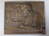 a bronze plaque of a man sitting at a desk