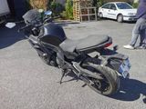 a black motorcycle parked in a parking lot with a man standing next to it
