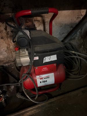 an image of a red air compressor in a dirty room