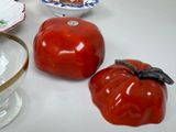 a red tomato sitting next to a glass bowl and a glass bowl with a tomato on it